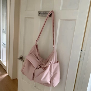 Detail of pink canvas crossbody bag featuring multi-pocket design and adjustable strap