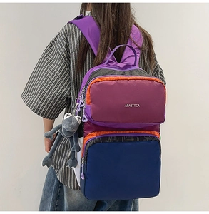 Close-up of color-block backpack with purple and orange panels and plush frog pendant