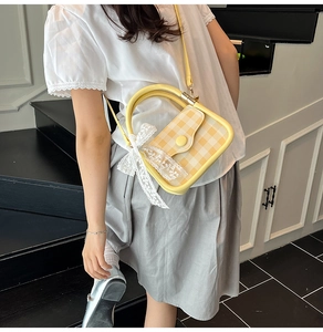 Detail of yellow plaid handbag featuring a white lace bow and gold metal handle