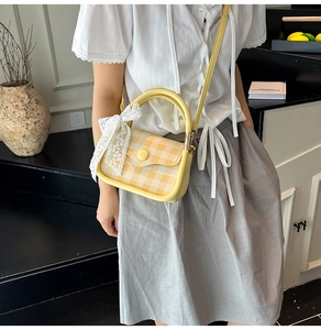 Detail of yellow gingham crossbody bag with lace bow and stylish round handle for women