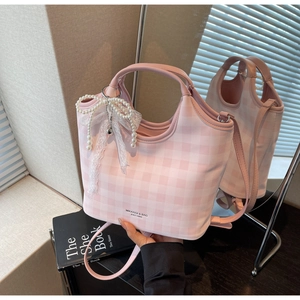 Detailed view of pink plaid tote bag with brand logo and pearl bow charm accessory