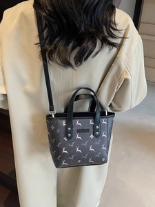 Sac seau marron foncé à imprimé cerf et rivets porté par un mannequin en trench-coat chic