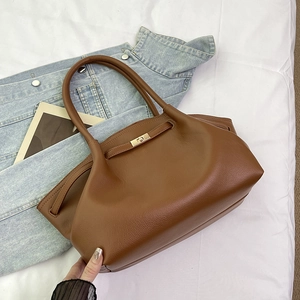 Detailed view of brown litchi pattern leather bag featuring a gold metal twist lock closure