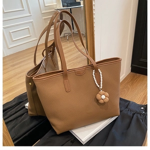 Texture détaillée d'un sac cabas marron en similicuir avec charm fleur et perles