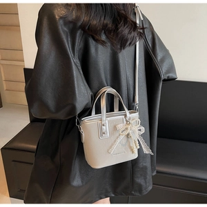 Silver mini bucket bag with lace bow and pearl pendant shown on a model's shoulder