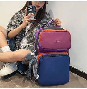 Detailed view of a multi-compartment color-block nylon backpack with plush charm