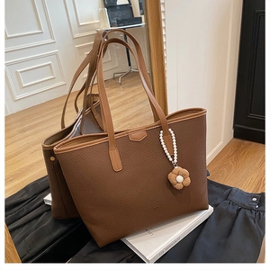 Détail du sac cabas marron foncé avec chaîne en perles et breloque fleur en cuir