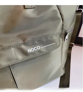 Détail macro du sac fourre-tout en nylon vert olive avec texte NOCO et fermeture argent