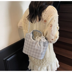Close-up of grey and white checkered tote bag with a pearl lace bow charm detail