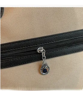 Close-up of smooth metal zipper and silver pendant on beige canvas travel tote bag