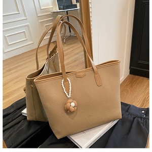 Détail du cabas en cuir grainé marron avec charm perle fleurie et fines bandoulières