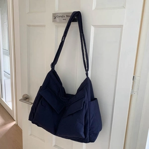 Detail of navy blue quilted messenger bag with large front pockets and wide strap