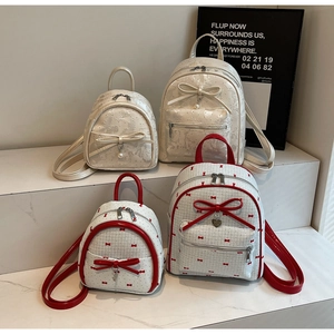 Detail view of mini backpacks in bow and lattice styles with pearl charms on marble