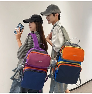 Outdoor shot of large capacity color-block backpacks with cute frog plush pendants