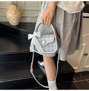 Detail of light gray gingham handbag with lace bow and silver U-shaped handle