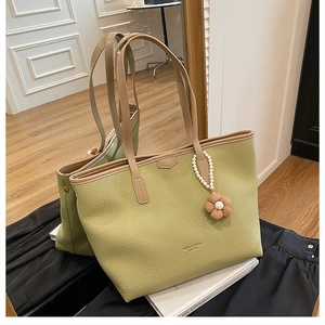Détail d'un sac cabas vert clair en cuir grainé avec pendentif perle et fleur