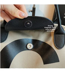 Close-up of a strong magnetic clasp on a canvas tote bag with leather flap detail