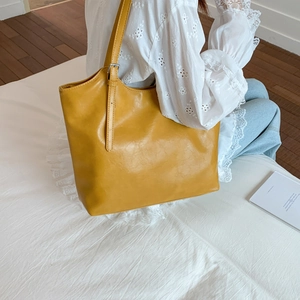 Detalle del bolso tote amarillo mostaza con textura de cuero y correa de hombro ajustable
