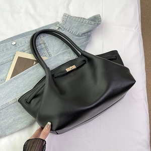 Close-up of black lychee-textured tote bag featuring a polished gold metal twist lock closure