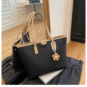 Détail du sac cabas noir en cuir grainé avec anses bicolores et bijou de sac