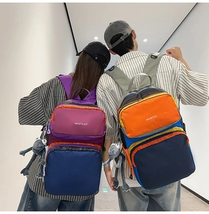 Detail of color-block nylon backpacks featuring multiple zippers and frog pendants