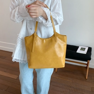 Detalle del bolso tote amarillo con correa ajustable y hebilla metálica en piel sintética lisa