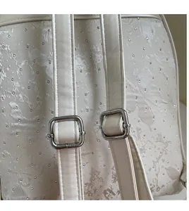 Detail of floral embossed cream backpack showing silver metal strap adjustment buckles