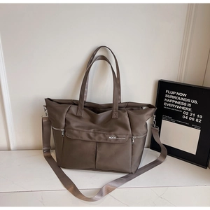 Détail d'un sac cabas en nylon marron foncé avec logo NOCO blanc et finitions en métal