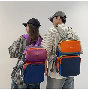 Close-up of a large capacity backpack with contrasting colors and plush frog pendant