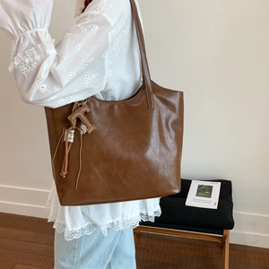 Bolso tote vintage de cuero marrón con colgante en T visto desde una perspectiva lateral