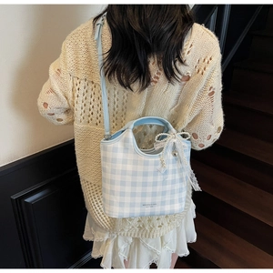 Detail of blue plaid tote bag with lace pearl bow charm and elegant brand logo design