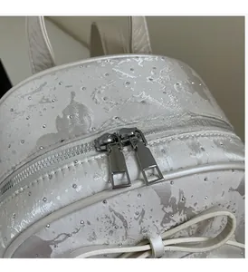 Detail of shimmering pearl white fabric with rhinestones and silver bow zipper on backpack