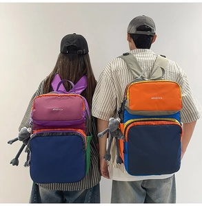 Detail of multi-compartment color block backpack with brand logo and plush pendant