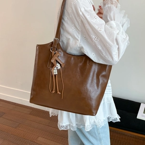 Detalle de un bolso tote grande marrón vintage con colgante de caballo y borlas