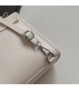 Detailed macro view of silver metal buckles and cream lychee grain leather on mini backpack