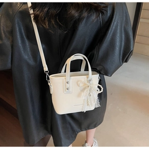 Detail of white mini bucket bag with pearl lace bow and fashion bags typography