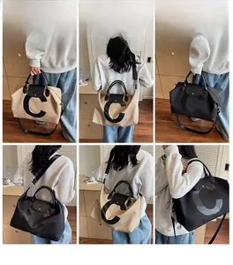 Detail view of large travel tote bags in beige and black with leather-style handles