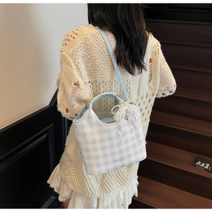 Plaid tote bag with pearl bow charm shown being carried by a model on stairs