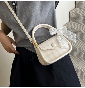 Close-up of cream plaid crossbody bag featuring a delicate white lace bow detail
