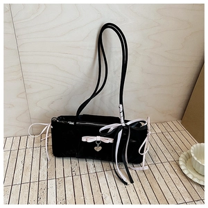 Detail of black velvet shoulder bag featuring pink ribbon bows and a heart pendant