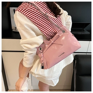 Borsa rosa in pelle verniciata con catena d'argento e fiocco sulla spalla della modella