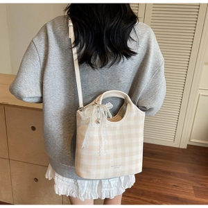 Milk tea plaid tote bag with pearl bow charm shown being worn in a stylish home setting