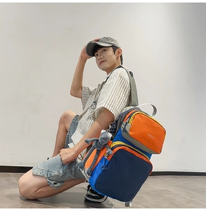 Outdoor color-block backpack with brand logo and plush monkey charm on female model