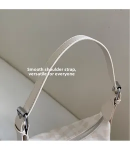 Gros plan sur la bandoulière en cuir PU et boucle argentée d'un sac hobo à carreaux