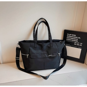 Gros plan du sac cabas en nylon noir montrant la poche avant et le logo NOCO blanc