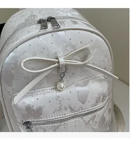 Detailed view of pearl white mini backpack with jacquard texture and bow pendant