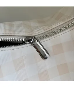 Gros plan sur la fermeture éclair en métal argenté du sac hobo à carreaux beige