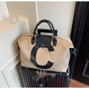 Detail of canvas travel tote with leather handles on a suitcase showing strap attachment