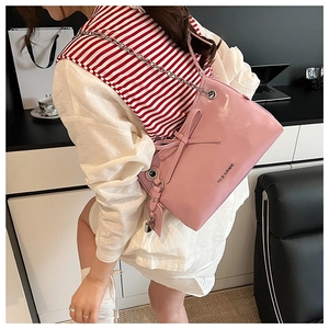 Dettaglio borsa tote in pelle lucida rosa con fiocco e ciondolo lucchetto argento