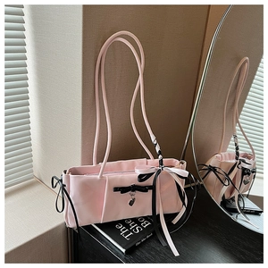 Detail of pink satin shoulder bag featuring black bows and a metallic heart pendant